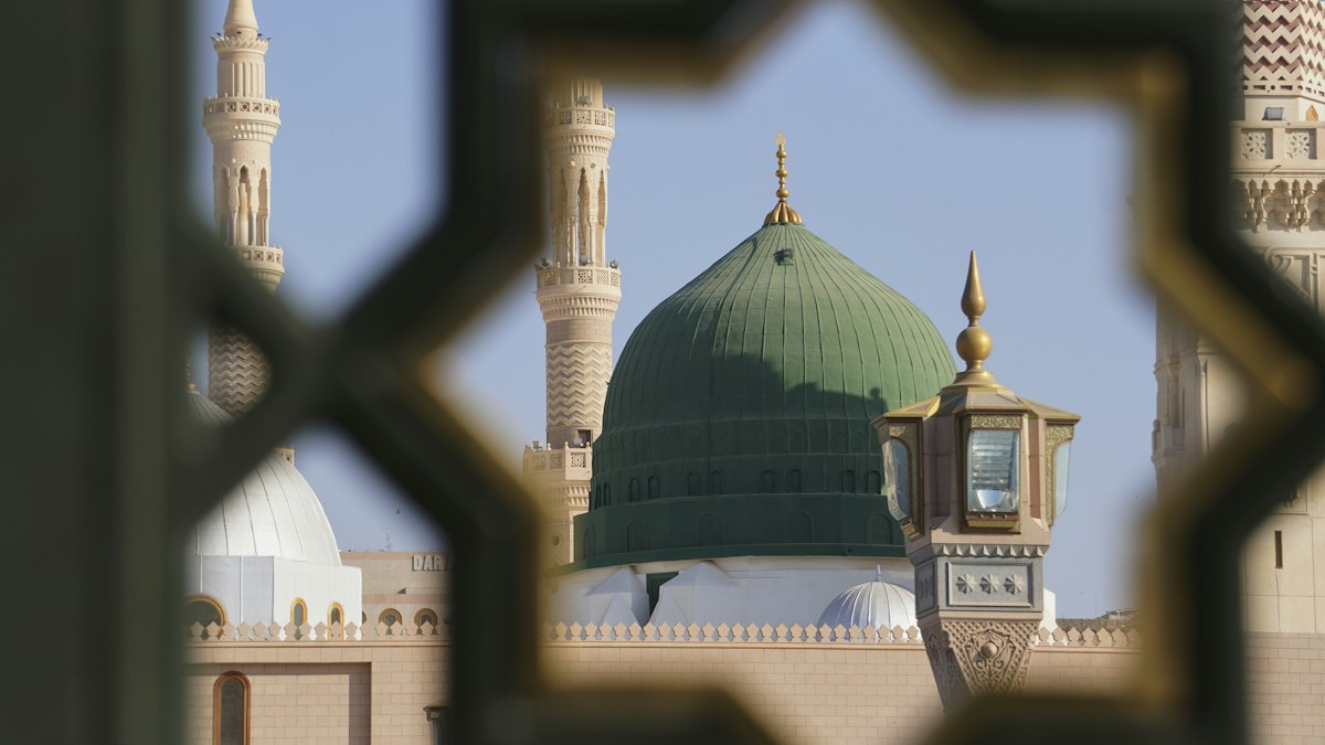 The Green Dome of Masjid an-Nabawi in Madinah seen through a carved lattice